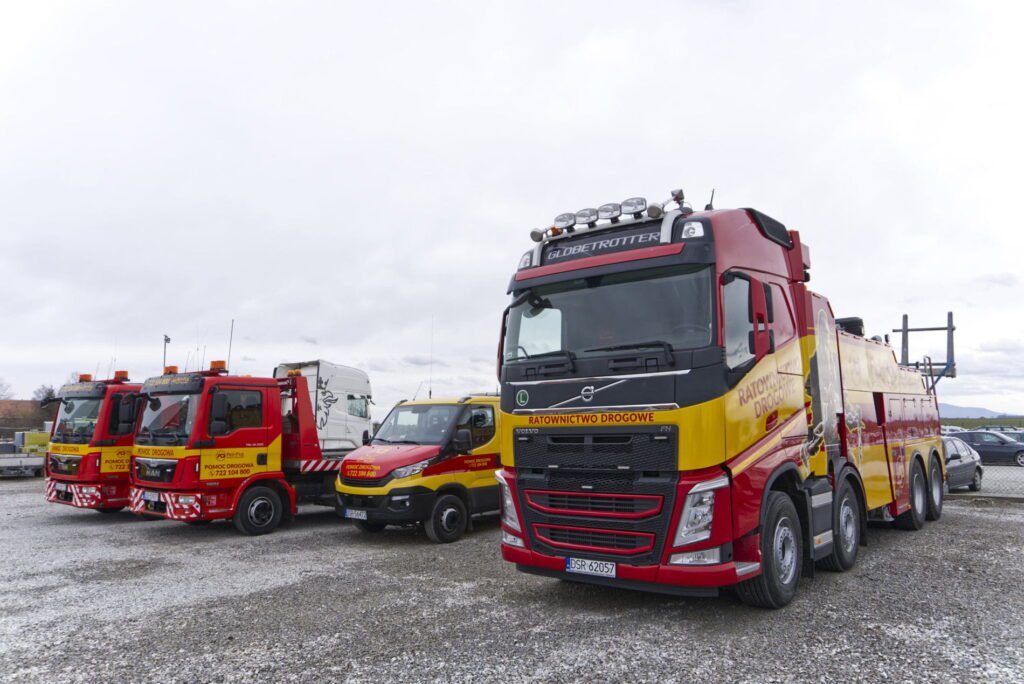 Holowanie ciężarówek Chojnów – nowoczesny holownik i lawety zaparkowane na placu firmy.